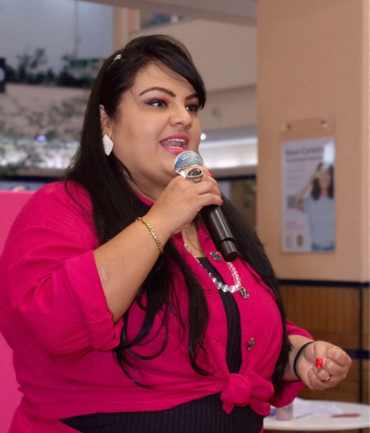 Helena Custódio falando ao microfone em um evento